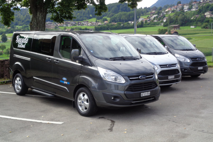 Ford Tourneo Custom in orange und grau vor einem mit Lichterketten geschmückten Haus